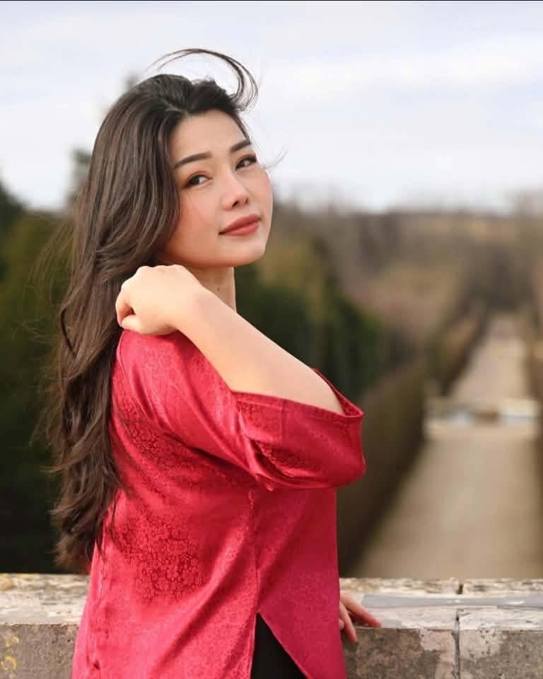 Emilie Hue mặc áo dài đỏ trong một công viên mùa đông